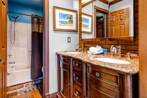 Bathroom with double vanity, shower / tub combo, decorative backsplash, and light wood-style floors