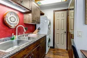 Laundry area with stacked washer / dryer and dark wood-style flooring