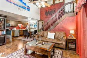 Living area with ceiling fan, dark wood-type flooring, and a high ceiling