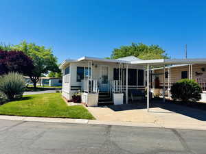 Manufactured / mobile home with a front yard, a carport, and concrete driveway