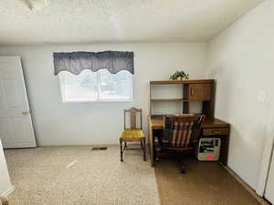 Office area featuring a textured ceiling and light carpet