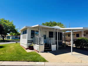Manufactured / mobile home with a front lawn, a carport, and concrete driveway