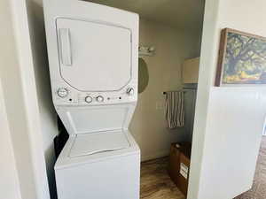 Laundry area featuring stacked washer and clothes dryer and wood finished floors