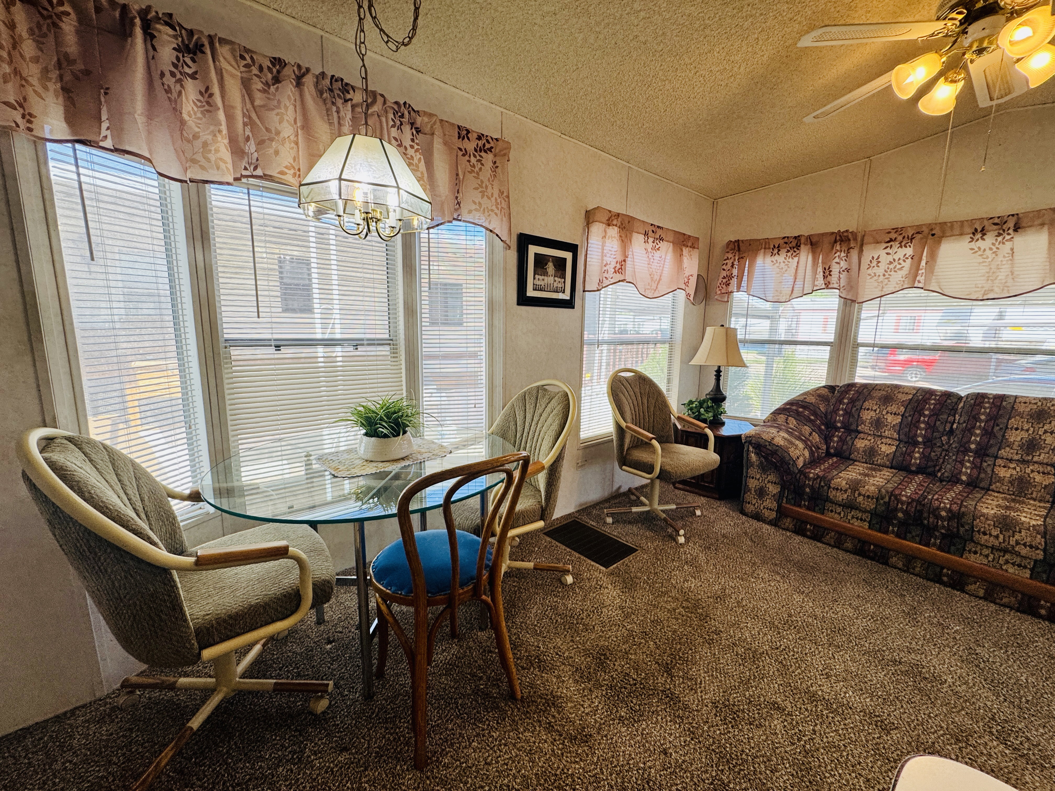 Carpeted dining space with a ceiling fan and hanging lights
