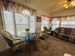 Carpeted dining space with a ceiling fan and hanging lights