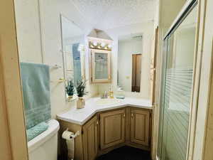 Bathroom with a stall shower, vanity, and a textured ceiling