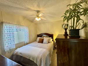 Bedroom featuring a textured ceiling, ceiling fan, and carpet floors