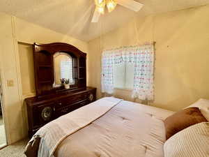 Carpeted bedroom featuring ceiling fan, a textured ceiling, and a textured wall