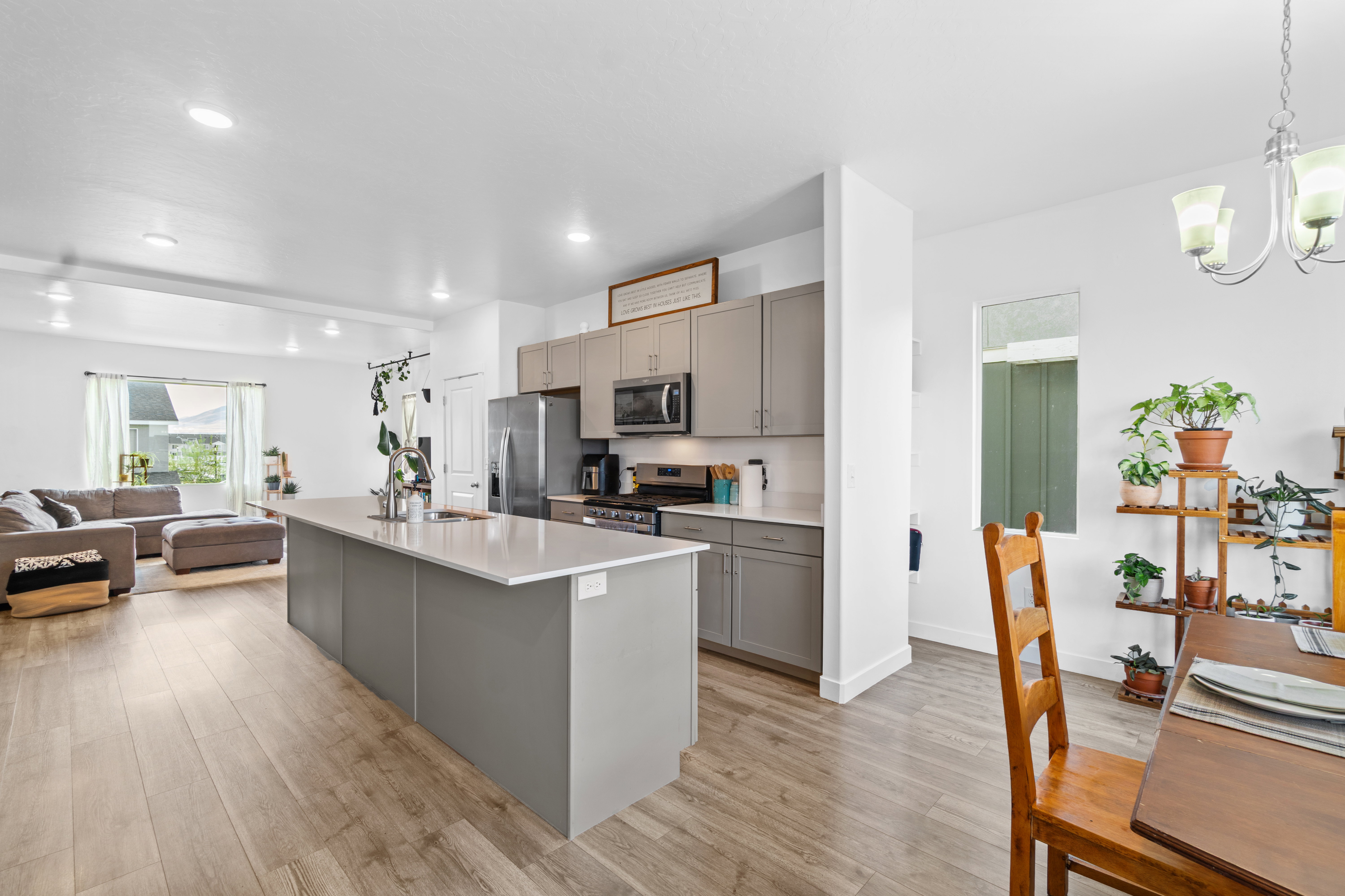 Kitchen featuring open floor plan, gray cabinets, stainless steel appliances, and an island with sink