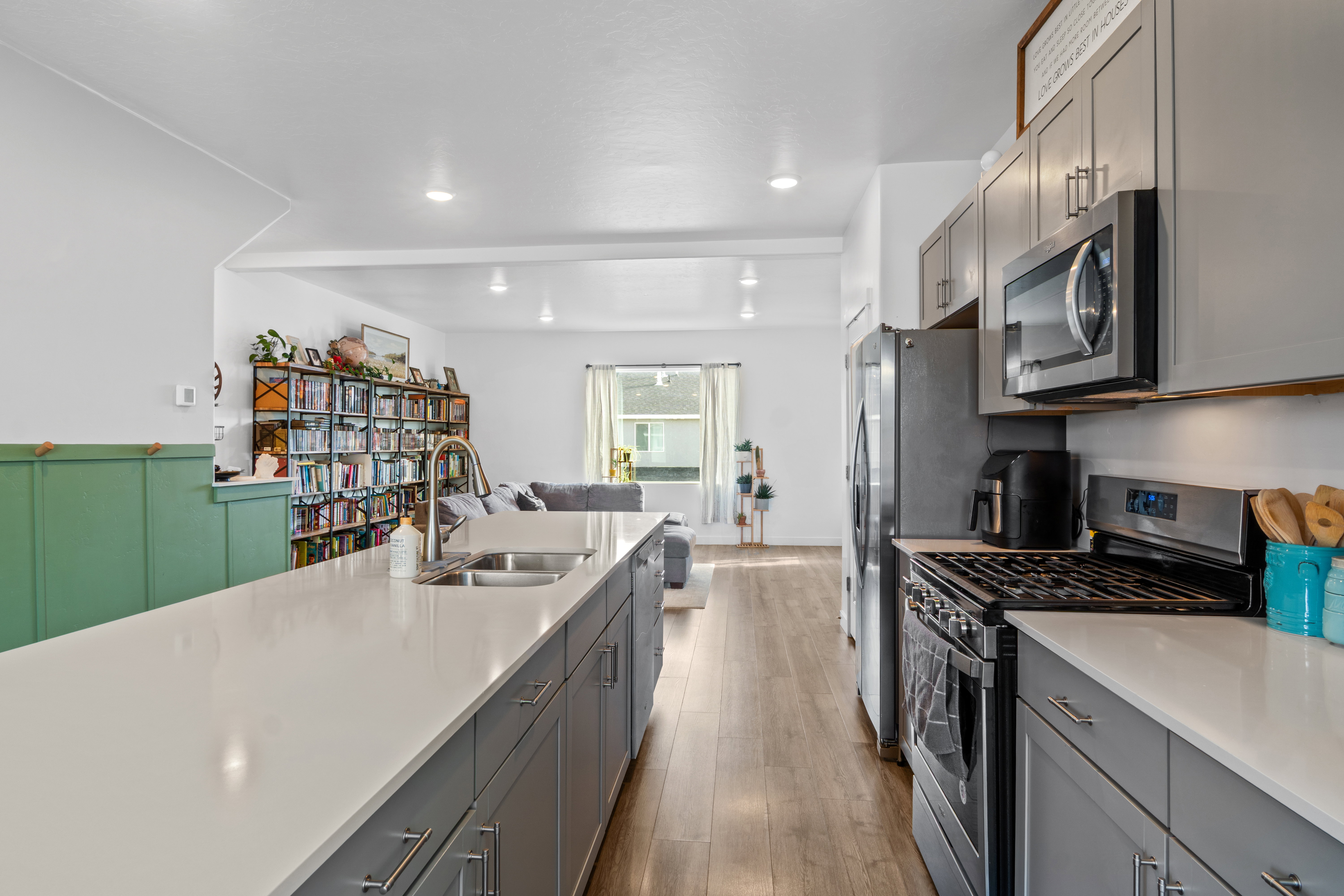 Kitchen featuring stainless steel appliances, gray cabinetry, open floor plan, and quartz counters