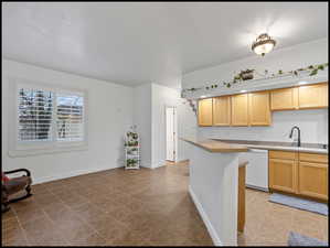 Kitchen with light countertops, light wood finish cabinetry, dishwasher, and a breakfast bar area
