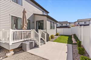 Fenced backyard featuring a wooden deck and a patio