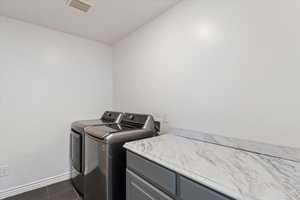 Laundry room with washer and dryer and dark tile patterned flooring