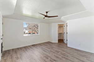 Unfurnished bedroom with light wood-style floors, a textured ceiling, ceiling fan, and a spacious closet