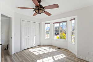 Unfurnished bedroom with light wood-style flooring, a ceiling fan, and a closet
