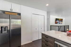 Kitchen with stainless steel appliances, recessed lighting, light stone counters, and white cabinetry
