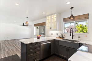 Two tone kitchen with hanging light fixtures, glass fronted cabinets, stainless steel dishwasher, decorative backsplash, and a peninsula
