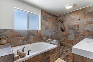 Bathroom featuring vanity, a walk in shower, and a garden tub