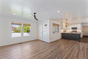 Unfurnished living room featuring recessed lighting, ceiling fan, dark wood-style flooring, and a textured ceiling