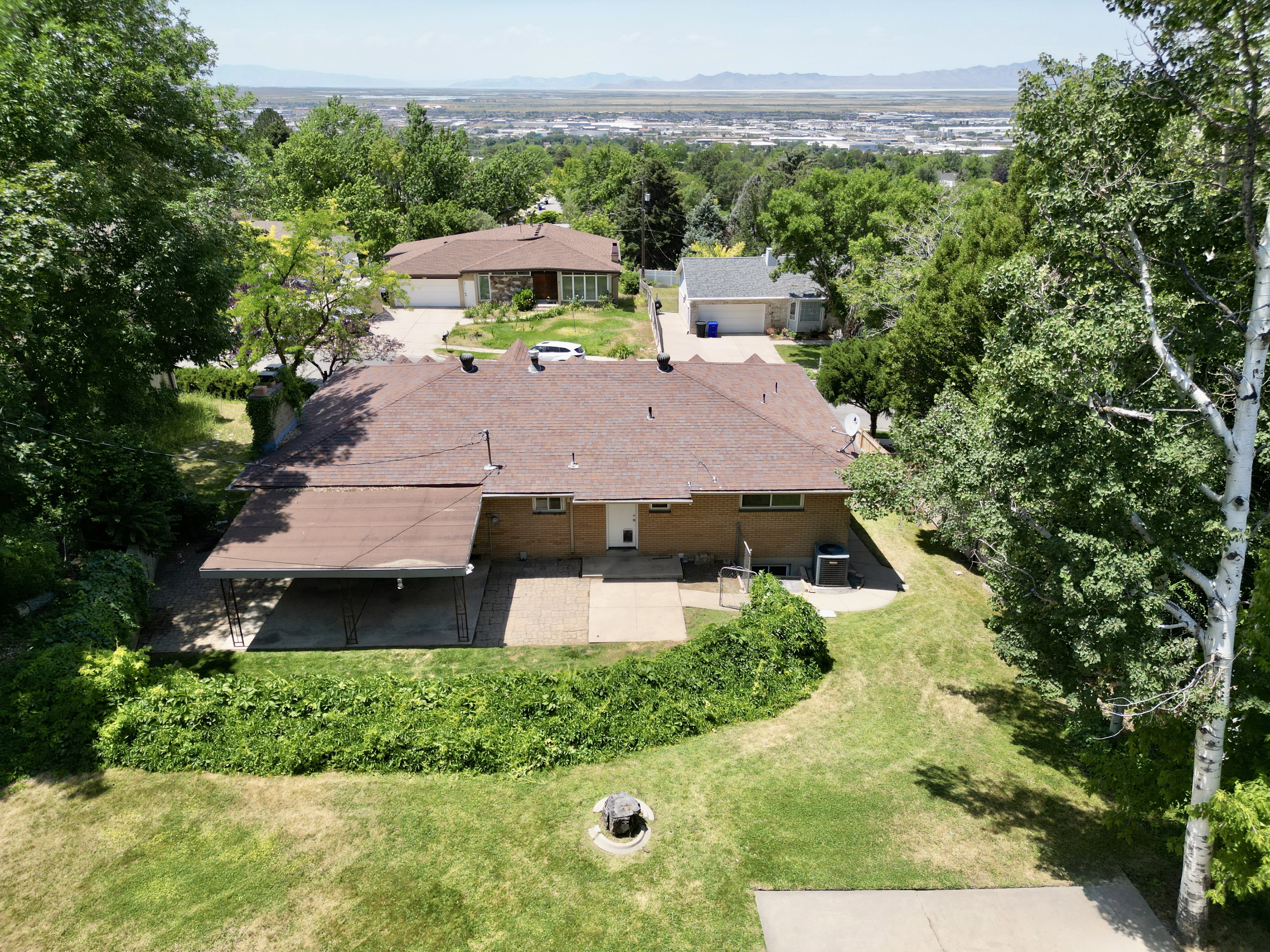 Aerial view of property and surrounding area featuring a mountainous background and a tree filled landscape