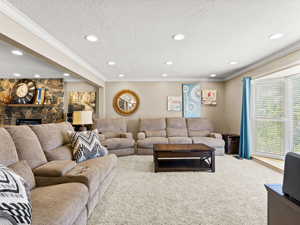 Living room with a fireplace, a textured ceiling, carpet flooring, crown molding, and recessed lighting
