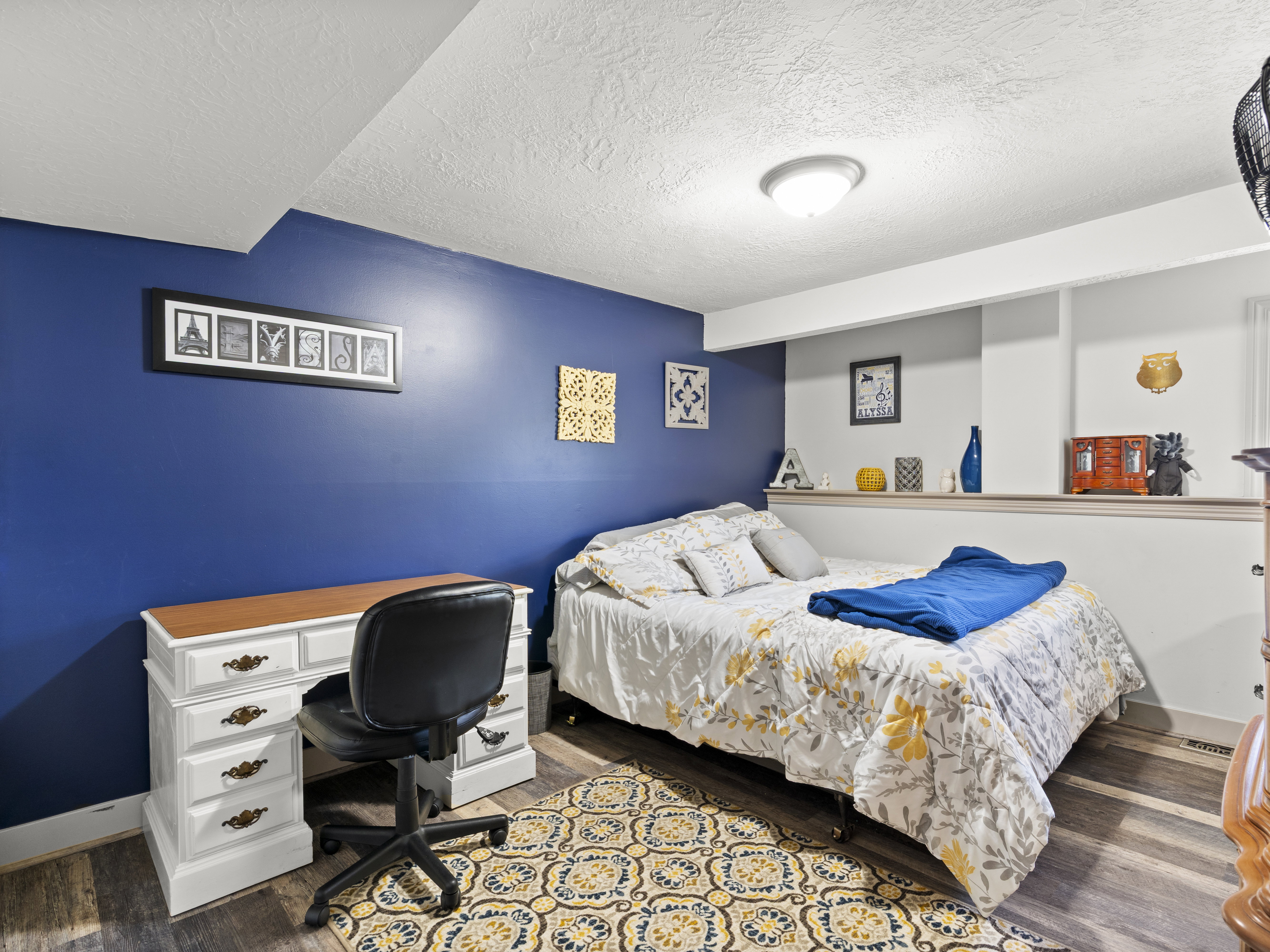 Bedroom with a textured ceiling, dark wood-style flooring, and a desk