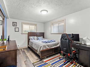 Bedroom with a desk, wood finished floors, and a textured ceiling