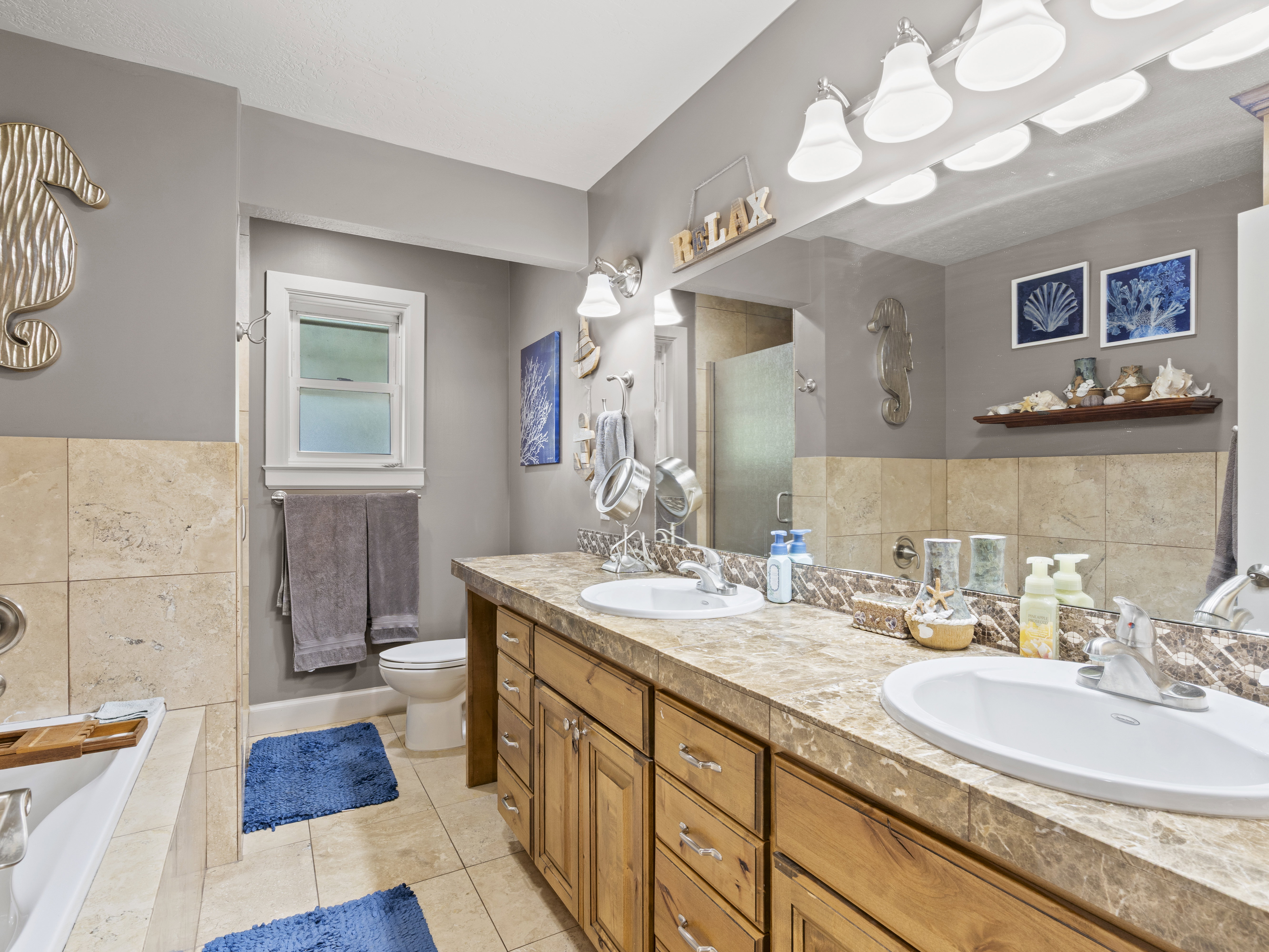 Full bathroom featuring a bath, double vanity, light tile patterned floors, and a walk in shower