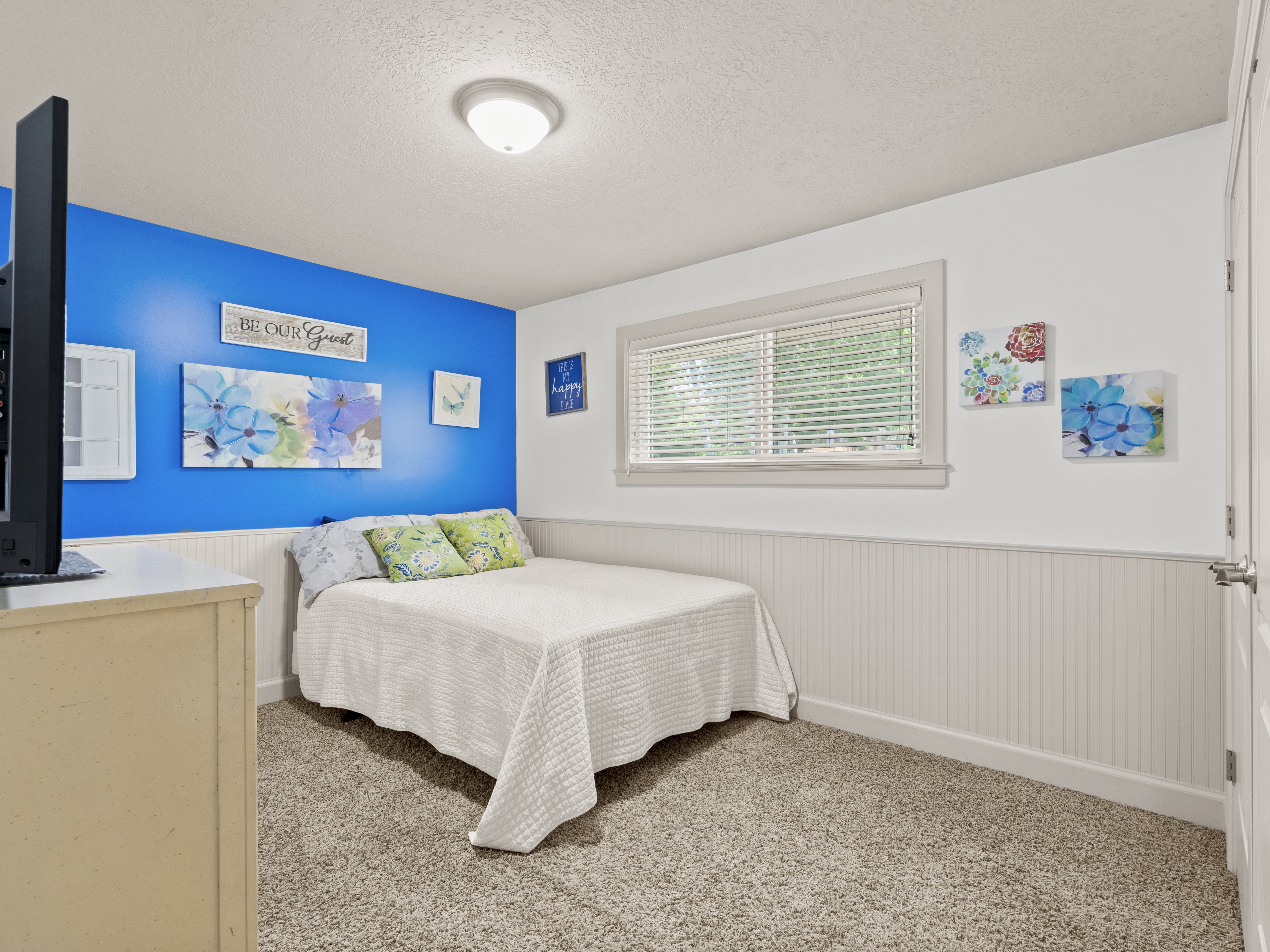 Bedroom featuring a wainscoted wall, a textured ceiling, and light carpet