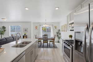 Kitchen with stainless steel appliances, light flooring, light stone countertops, hanging lights, and open floor plan
