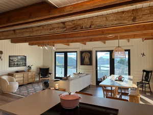 Living area with dark wood-style floors, wooden walls, and a wood ceiling with exposed beams