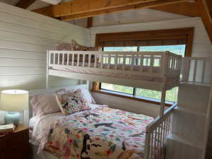 Bedroom featuring wood walls and lofted ceiling