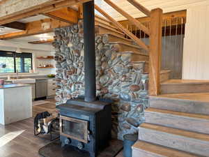 Detailed view of a wood stove, wood finished floors, and stainless steel dishwasher