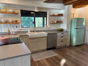Kitchen featuring open shelves, freestanding refrigerator, dark wood-type flooring, and stainless steel dishwasher