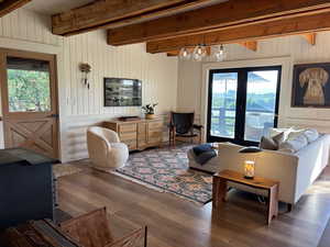 Living area featuring beam ceiling, wood walls, dark wood-style floors, and a wood stove