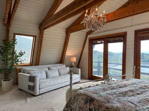 Bedroom with access to exterior, carpet flooring, a chandelier, wooden walls, and multiple windows
