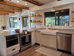 Kitchen with open shelves, a peninsula, stainless steel appliances, dark wood-style floors, and a wood ceiling with exposed beams