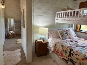 Bedroom with carpet flooring and wood walls