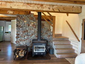 Staircase featuring a wood ceiling with exposed beams, wood finished floors, and a wood stove