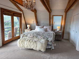 Carpeted bedroom with wood walls, access to exterior, a chandelier, wooden ceiling, and multiple windows
