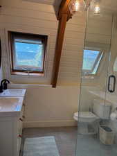 Full bath featuring vanity, a stall shower, light tile patterned floors, plenty of natural light, and vaulted ceiling with beams