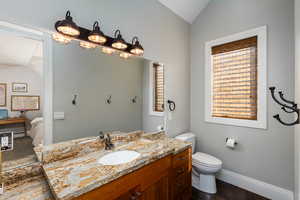 Half bath featuring vanity, vaulted ceiling, and connected bathroom