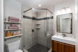 Bathroom featuring a stall shower, vanity, a textured ceiling, and recessed lighting