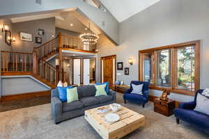 Carpeted living room with lofted ceiling, a chandelier, and stone finish flooring