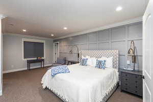 Bedroom with a decorative wall, recessed lighting, dark colored carpet, ornamental molding, and an accent wall