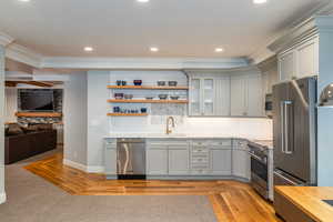 Kitchen featuring backsplash, crown molding, glass fronted cabinets, stainless steel appliances, and gray cabinetry