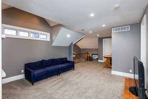 Sitting room with an upstairs landing, light colored carpet, and recessed lighting