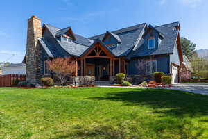 View of front facade with covered porch, stone siding, a chimney, and roof mounted solar panels