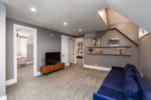 Carpeted living room featuring a textured ceiling and recessed lighting