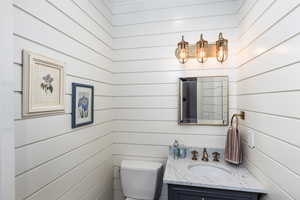 Half bath featuring vanity and wooden walls